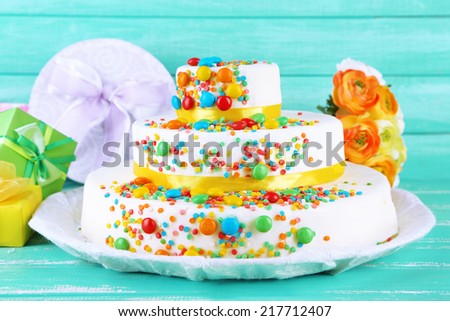 Beautiful tasty birthday cake and gifts on color wooden background