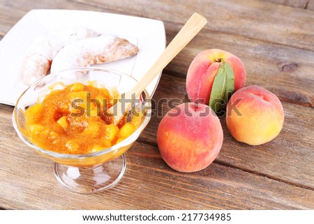 tasty peach jam with fresh peaches and croissants on wooden table