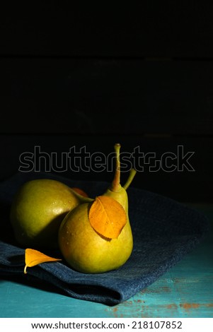 Ripe tasty pears on wooden table, on dark background