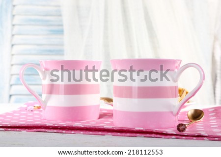 Two mugs of coffee on napkin on table on white curtain background