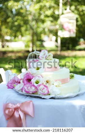 Beautiful wedding cake with flowers on table, outdoors