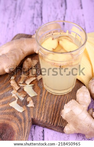 Ginger drink and ginger root and napkin on cutting board on wooden background