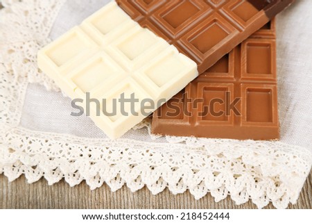 Chocolate bars on napkin on wooden background
