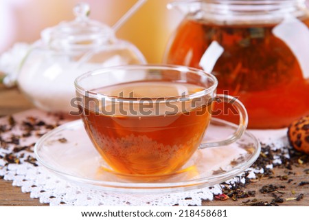 Teapot and cup of tea on table on light background