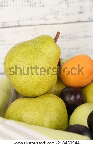 Ripe fruits in crate on table on wooden background