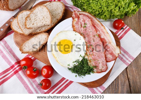 Scrambled eggs with bacon and vegetables served on plate on napkin