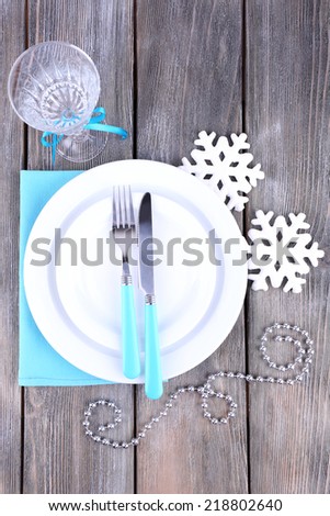 White plates, fork, knife, goblet and Christmas tree decoration on wooden background