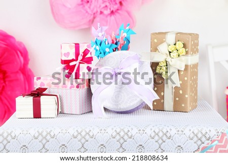 Wedding or birthday gifts on decorated table, on bright background