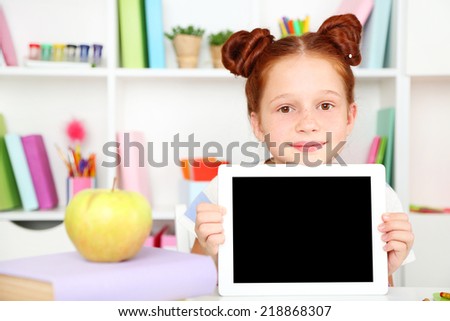 Cute girl with tablet at workplace in classroom