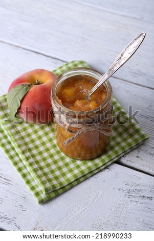 tasty peach jam with fresh peach on wooden table