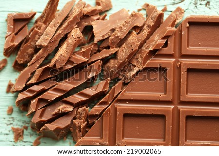 Milk chocolate bar on color wooden background