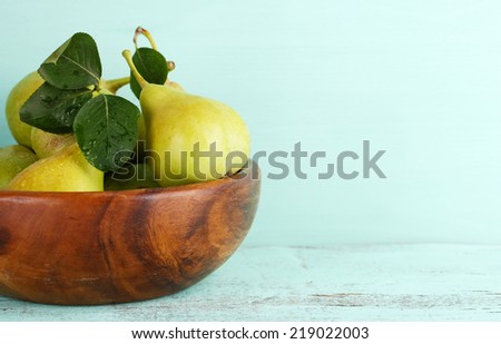 Ripe tasty pears in wooden bowl, on table
