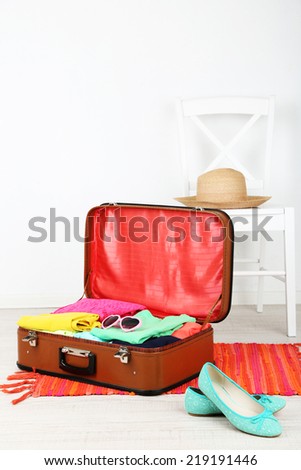 Female clothes in old suitcase on light background