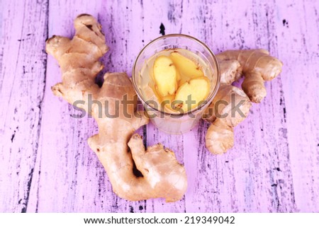 Ginger drink and ginger root on wooden background