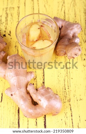 Ginger drink and ginger root on wooden background