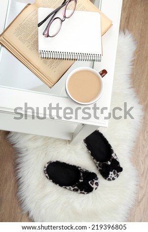Still life details, cup of coffee, book and glasses on table, on home interior background