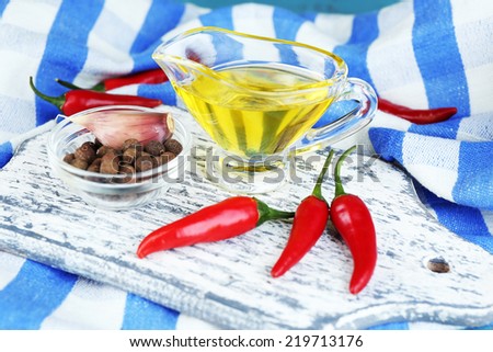 Set of spices and olive oil in glass sauce-boat, in cutting board, on color  wooden background