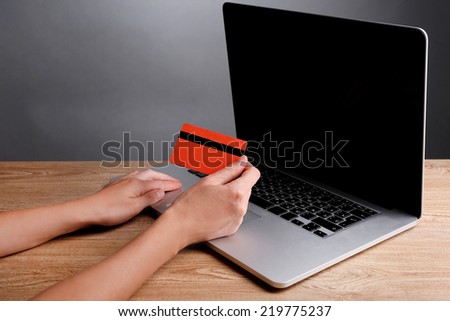 Hand holding credit card to buy online, on gray background