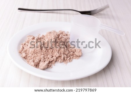 Whey protein powder on plate with scoop on wooden background
