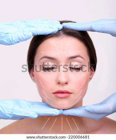 Face massage. Hands in rubber gloves touching face of young woman (with arrows)
