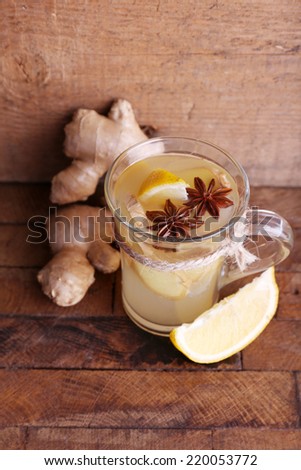 Cup of ginger drink with lemon on wooden background