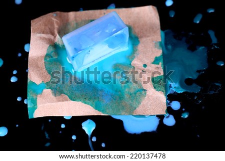 Watercolor paint cube and spilled paint isolated on black