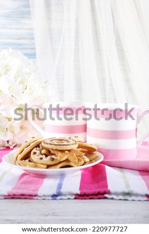 Two mugs of coffee with biscuits on napkin on table on white curtain background