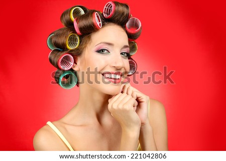 Beautiful girl in hair curlers on red background