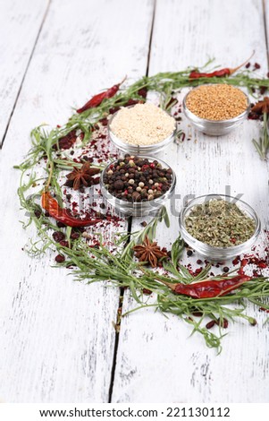 Spices in glass round bowls with herbs and chilly pepper on wooden background