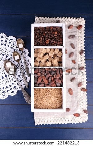 Wooden box with set of coffee and cocoa beans, sugar cubes on wooden background