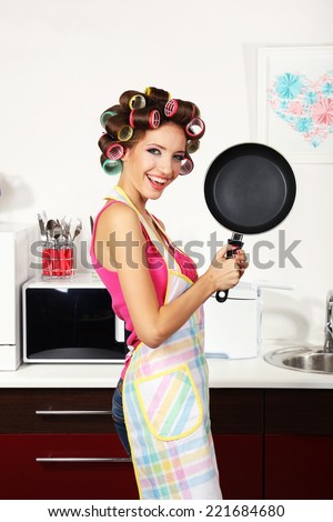 Beautiful girl in hair curlers in kitchen