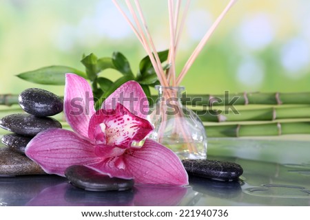 Spa stones, sticks, bamboo branches and lilac orchid on table on natural background
