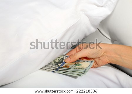 Woman hiding money under pillow at home
