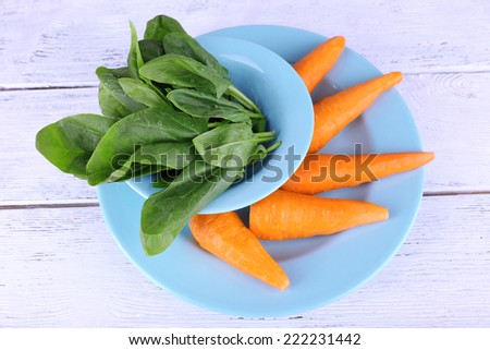 Carrots and sorrel on blue round plate on wooden background