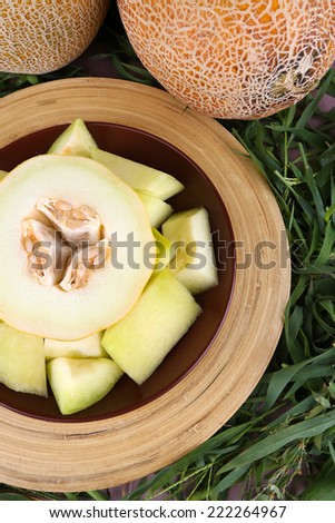 Melon on brown plate on bamboo plate on grass background