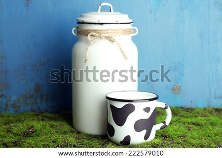 Retro can for milk and mug of milk on wooden background
