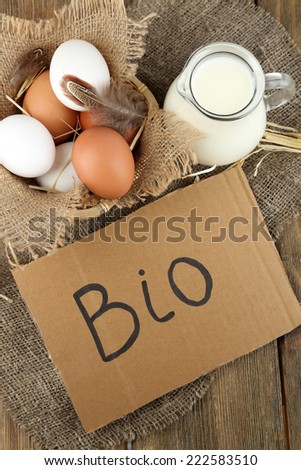 Eggs and fresh milk in glass jug with inscription BIO  , on wooden background. Organic products concept