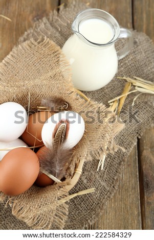 Eggs and fresh milk in glass jug, on wooden background. Organic products concept