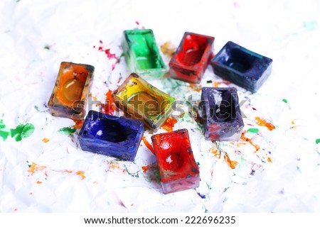 Watercolor paint cubes and spilled paint on white paper background