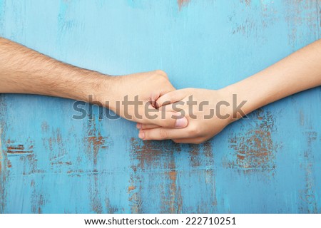 Loving couple holding hands close-up on wooden background