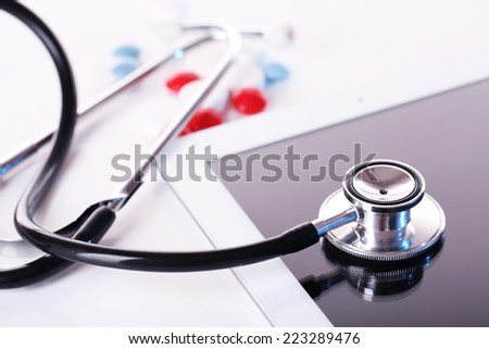 Stethoscope, pills, PC tablet on light background. Medicine concept