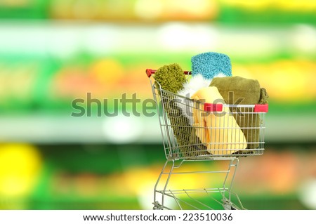 Shopping concept. Shopping cart with colorful carpets and plaids on shop background