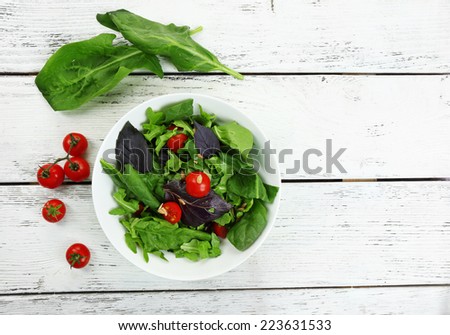 Fresh green salad in bowl on wooden table