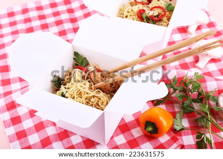 Chinese noodles and sticks in takeaway boxes on fabric background