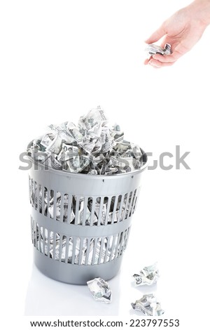 Hand throwing money into trash can isolated on white