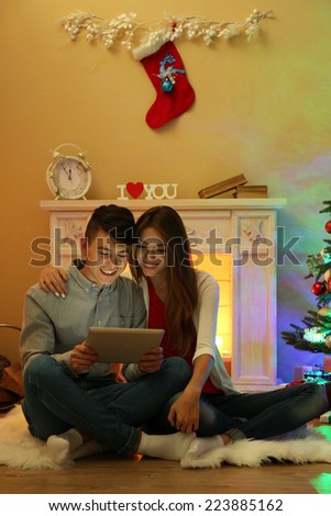 Couple near fireplace in  Christmas decorated house with tablet
