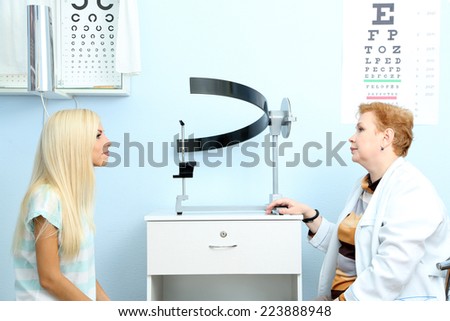 Optometry concept - pretty young woman having her eyes examined by eye doctor