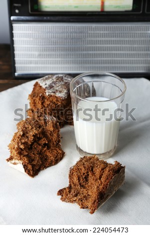 Rye bread and glass of milk on white fabric napkin on wooden table on radio set and light wall background
