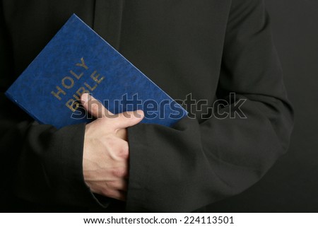 Man holding Bible on dark background