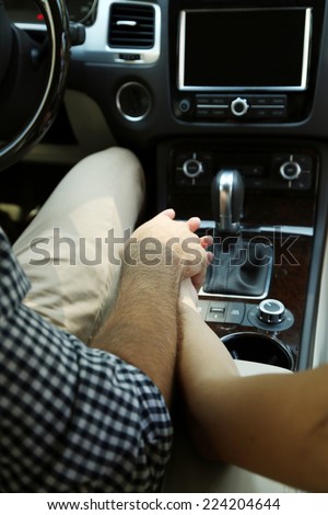 Loving couple holding hands in car close-up